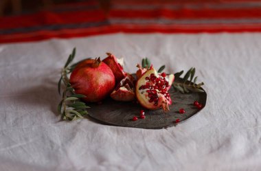Eski bir retro plaka üzerinde Türk Narı ve zeytin dalı ile Still Life 'ın görüntüsü. Karanlık ahşap arka plan, antika bakır plaka. Taze taze nar, açık nar ve tohum.