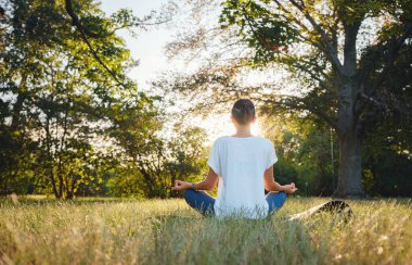Genç Asyalı bir kadın sabah veya akşam parkta meditasyon yapıyor sağlıklı bir kadın şehir parkında yoga yapıyor. Farkındalık, kararlılık, sağlıklı alışkanlıklar ve denge konsepti