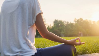 Genç Asyalı bir kadın sabah veya akşam parkta meditasyon yapıyor sağlıklı bir kadın şehir parkında yoga yapıyor. Farkındalık, kararlılık, sağlıklı alışkanlıklar ve denge konsepti