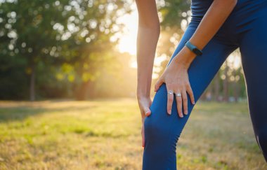 Akşam parkında diz ağrısı olan bir kadın. Sakat dizini tutun. Spor yapan kadınların eklem ağrısından muzdarip düşük kesimi. Egzersiz konseptinden kaynaklanan kaza.