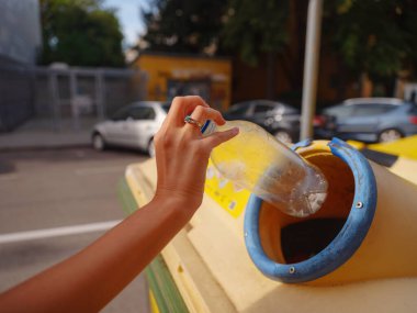 Avrupa caddesinde plastik şişe geri dönüşüm kutusu satan bir kadın. Dünyayı ve çevre bakımını kurtarmak için çöp kutusuna atılmadan önce atık ayıklama çöplüğü. Kirlilik çöpü geri dönüşüm yönetimi kavramı