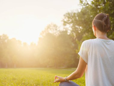 Genç Asyalı bir kadın sabah veya akşam parkta meditasyon yapıyor sağlıklı bir kadın şehir parkında yoga yapıyor. Farkındalık, kararlılık, sağlıklı alışkanlıklar ve denge konsepti