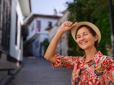 Antalya, Türkiye 'ye yaz seyahati. Kırmızı elbiseli genç Asyalı kadın eski şehir Kalechi 'den geçiyor. Kadın turist ilginç yerler ve popüler turistik ilgi alanları keşfediyor.