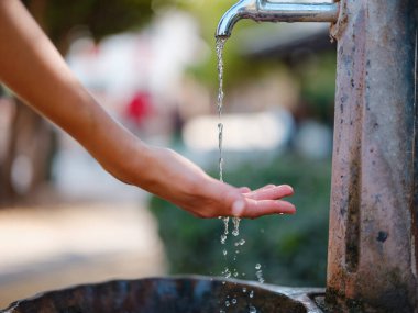 Antalyas eski kasaba: Kadın eli zarif bir şekilde çeşmeye uzanır, tarihi cazibenin ortasında ferahlatıcı bir vaha, tarihten ve sükunetten bir yudum sunar