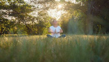 Genç Asyalı bir kadın sabah veya akşam parkta meditasyon yapıyor sağlıklı bir kadın şehir parkında yoga yapıyor. Farkındalık, kararlılık, sağlıklı alışkanlıklar ve denge konsepti