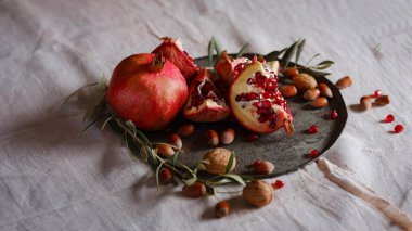 Eski bir retro plaka üzerinde Türk Narı ve zeytin dalı ile Still Life 'ın görüntüsü. Karanlık ahşap arka plan, antika bakır plaka. Taze taze nar, açık nar ve tohum.