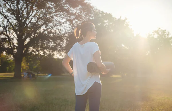 Şehir parkında sağlıklı aktif yaşam tarzı kavramı. Kadın yaz günü spor paspasıyla parkta yürürken, sağlık durumu, sağlık egzersizi ya da açık hava egzersizinden sonra ya da öncesinde.