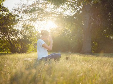 Genç Asyalı bir kadın sabah veya akşam parkta meditasyon yapıyor sağlıklı bir kadın şehir parkında yoga yapıyor. Farkındalık, kararlılık, sağlıklı alışkanlıklar ve denge konsepti