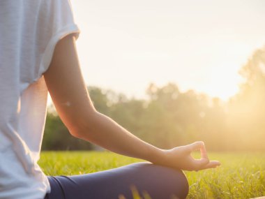 Genç Asyalı bir kadın sabah veya akşam parkta meditasyon yapıyor sağlıklı bir kadın şehir parkında yoga yapıyor. Farkındalık, kararlılık, sağlıklı alışkanlıklar ve denge konsepti
