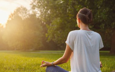 Genç Asyalı bir kadın sabah veya akşam parkta meditasyon yapıyor sağlıklı bir kadın şehir parkında yoga yapıyor. Farkındalık, kararlılık, sağlıklı alışkanlıklar ve denge konsepti