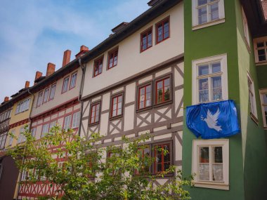 Avrupa 'ya bahar gezisi. Erfurt 'ta bir yerlerde eski tarihi evlerin ön cephesine manzaralı, mavi bayrak barış güvercini ev sakinlerinin ön cephesinde asılı.