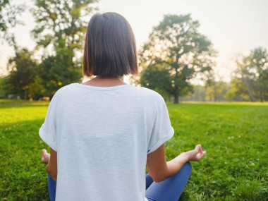 Genç Asyalı bir kadın sabah veya akşam parkta meditasyon yapıyor sağlıklı bir kadın şehir parkında yoga yapıyor. Farkındalık, kararlılık, sağlıklı alışkanlıklar ve denge konsepti