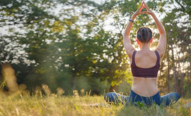 Genç Asyalı bir kadın sabah veya akşam parkta meditasyon yapıyor sağlıklı bir kadın şehir parkında yoga yapıyor. Farkındalık, kararlılık, sağlıklı alışkanlıklar ve denge konsepti