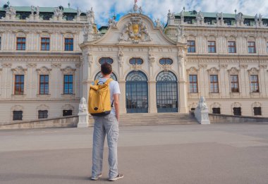 Erkek turist Avusturya 'da, başkent Viyana' da seyahat ediyor. Avrupa 'ya yaz erkek yalnız gezisi, Barok tarzı Belvedere sarayı yakınlarında parkta yürüyen mutlu genç adam..