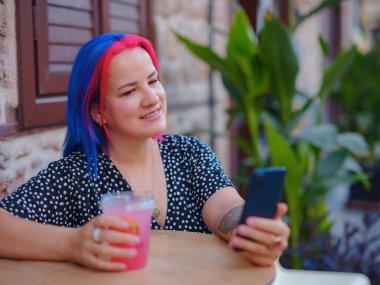 Antalya 'da yaz yürüyüşü. Renkli saçlı ve elbiseli bir kadın büyüleyici eski şehir olan Antalya 'da gezintiye çıkıyor. Arkadaşlarıyla ya da aileleriyle iletişim kurmak için akıllı telefon kullanıyor ya da uygulamalar kullanıyor.