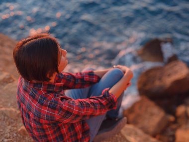 İspanya, Benidorm 'da kayalık sahilde yürüyüş yapan genç bir kadın. Dalgalı denizi ve körfezi izliyorum. Gezgin, huzurlu doğa manzarasında özgürlüğün tadını çıkarıyor.