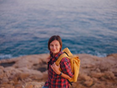 İspanya, Benidorm 'da kayalık sahilde yürüyüş yapan genç bir kadın. Dalgalı denizi ve körfezi izliyorum. Gezgin, huzurlu doğa manzarasında özgürlüğün tadını çıkarıyor.