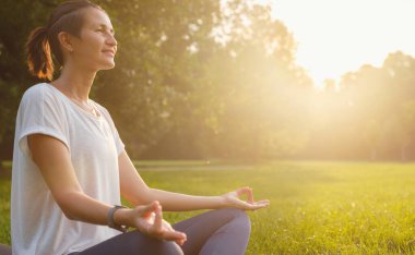 Genç Asyalı bir kadın sabah veya akşam parkta meditasyon yapıyor sağlıklı bir kadın şehir parkında yoga yapıyor. Farkındalık, kararlılık, sağlıklı alışkanlıklar ve denge konsepti
