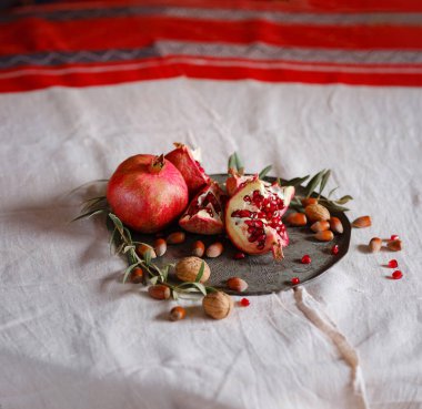 Eski bir retro plaka üzerinde Türk Narı ve zeytin dalı ile Still Life 'ın görüntüsü. Karanlık ahşap arka plan, antika bakır plaka. Taze taze nar, açık nar ve tohum.