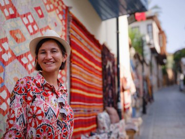 Antalya, Türkiye 'ye yaz seyahati. Kırmızı elbiseli genç Asyalı kadın eski şehir Kalechi 'den geçiyor. Kadın turist ilginç yerler ve geleneksel turist halısı keşfediyor.