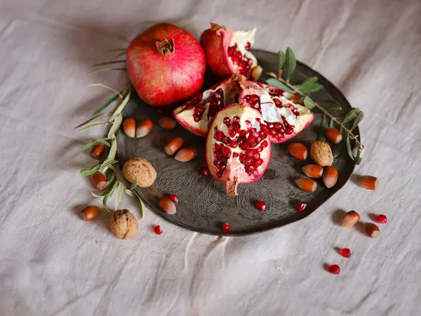 Eski bir retro plaka üzerinde Türk Narı ve zeytin dalı ile Still Life 'ın görüntüsü. Karanlık ahşap arka plan, antika bakır plaka. Taze taze nar, açık nar ve tohum.