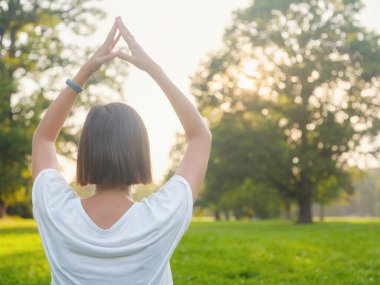 Genç Asyalı bir kadın sabah veya akşam parkta meditasyon yapıyor sağlıklı bir kadın şehir parkında yoga yapıyor. Farkındalık, kararlılık, sağlıklı alışkanlıklar ve denge konsepti