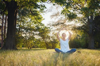 Genç Asyalı bir kadın sabah veya akşam parkta meditasyon yapıyor sağlıklı bir kadın şehir parkında yoga yapıyor. Farkındalık, kararlılık, sağlıklı alışkanlıklar ve denge konsepti