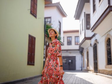 Antalya, Türkiye 'ye yaz seyahati. Kırmızı elbiseli genç Asyalı kadın eski şehir Kalechi 'den geçiyor. Kadın turist ilginç yerler ve popüler turistik ilgi alanları keşfediyor.