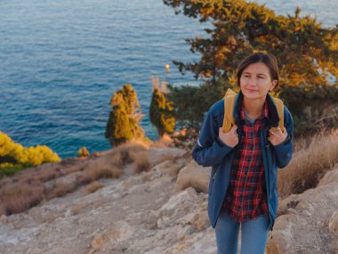 İspanya, Benidorm 'da kayalık sahilde yürüyüş yapan genç bir kadın. Dalgalı denizi ve körfezi izliyorum. Gezgin, huzurlu doğa manzarasında özgürlüğün tadını çıkarıyor.