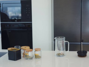 Bitki çayı, çay fincanı ve kahve makinası yapmak, beyaz modern mutfakta ev işi yapmak. Mutfakta çay içmek ve dinlenmek, güne olumlu düşüncelerle başlamak için.