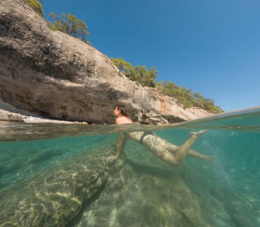 Denizde tropik tatil cennetinde bir kadın. Türk deniz kıyısında yaz tatili, Lycian Yolu 'nda plajlar, Türk Rivierası. Asyalı dişi su altı ve turkuaz okyanus çevresi.