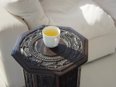 Küçük masada bir fincan çay. Sabahları evde çay içerim. Huzura ve çaya gülümsüyor güne olumlu düşüncelerle başlamak için içiyor.