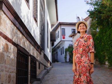 Antalya, Türkiye 'ye yaz seyahati. Kırmızı elbiseli genç Asyalı kadın eski şehir Kalechi 'den geçiyor. Kadın turist ilginç yerler ve popüler turistik ilgi alanları keşfediyor.