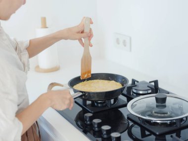 Beyaz modern mutfakta ev işi. Lezzetli omlet pişiren bir kadın kızartma tavasında.