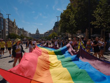 Prag, Çek Cumhuriyeti - 12 Ağustos 2023: Prag Onur Festivali Geçidi. Prag Gay Onur Yürüyüşü 'nde elinde kocaman bir gökkuşağı bayrağı olan insanlar. Wenceslas Meydanı 'nda Ulusal Müze önünde kalabalık var..