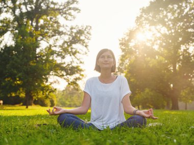 Genç Asyalı bir kadın sabah veya akşam parkta meditasyon yapıyor sağlıklı bir kadın şehir parkında yoga yapıyor. Farkındalık, kararlılık, sağlıklı alışkanlıklar ve denge konsepti