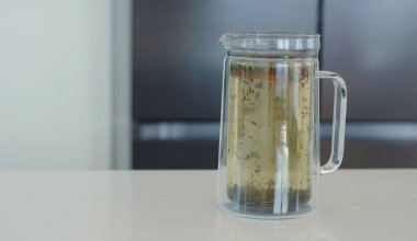 Bitki çayı, çay fincanı ve kahve makinası yapmak, beyaz modern mutfakta ev işi yapmak. Mutfakta çay içmek ve dinlenmek, güne olumlu düşüncelerle başlamak için.