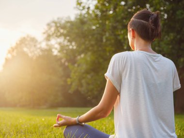 Genç Asyalı bir kadın sabah veya akşam parkta meditasyon yapıyor sağlıklı bir kadın şehir parkında yoga yapıyor. Farkındalık, kararlılık, sağlıklı alışkanlıklar ve denge konsepti