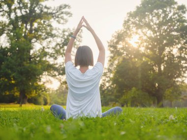 Genç Asyalı bir kadın sabah veya akşam parkta meditasyon yapıyor sağlıklı bir kadın şehir parkında yoga yapıyor. Farkındalık, kararlılık, sağlıklı alışkanlıklar ve denge konsepti