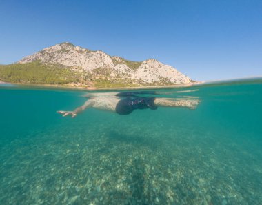 Bayramlarda genç erkek, Antalya Türkiye 'nin kristal berrak su plajında yüzmenin keyfini çıkarıyor. Kolları açık yüzen bir adam. Rahatla ve sakinleş.