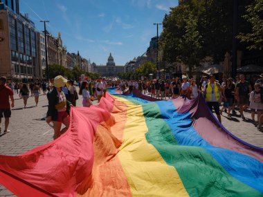 Prag, Çek Cumhuriyeti - 12 Ağustos 2023: Prag Onur Festivali Geçidi. Prag Gay Onur Yürüyüşü 'nde elinde kocaman bir gökkuşağı bayrağı olan insanlar. Wenceslas Meydanı 'nda Ulusal Müze önünde kalabalık var..