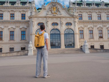 Erkek turist Avusturya 'da, başkent Viyana' da seyahat ediyor. Avrupa 'ya yaz erkek yalnız gezisi, Barok tarzı Belvedere sarayı yakınlarında parkta yürüyen mutlu genç adam..