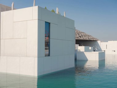Abu Dabi, Birleşik Arap Emirlikleri - 13 Ocak 2024: Louvre Abu Dabi ünlü müzesinin dışı. Zümrüt yeşili hendeği çevreleyen düz beyaz duvarlar süslü bir kubbe çatısı ile kaplı.