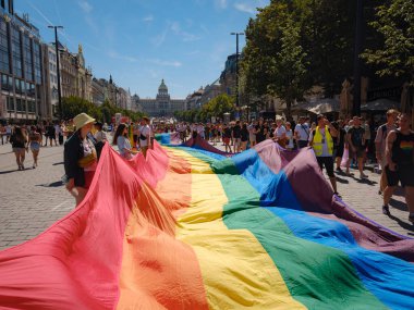 Prag, Çek Cumhuriyeti - 12 Ağustos 2023: Prag Onur Festivali Geçidi. Prag Gay Onur Yürüyüşü 'nde elinde kocaman bir gökkuşağı bayrağı olan insanlar. Wenceslas Meydanı 'nda Ulusal Müze önünde kalabalık var..