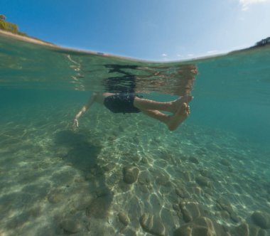 Bayramlarda genç erkek, Antalya Türkiye 'nin kristal berrak su plajında yüzmenin keyfini çıkarıyor. Kolları açık yüzen bir adam. Rahatla ve sakinleş.