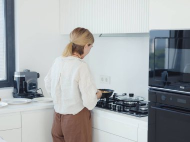 Lezzetli omlet pişiren bir kadın kızartma tavasında. ev işleri beyaz modern mutfakta.