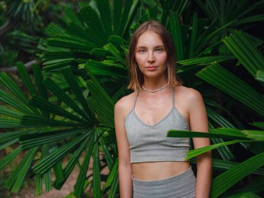 Tropikal ormanda güzel bir kadının portresi. Bronzlaşmış dişi ormanda egzotik bitkilerin arasında duruyor. Tayland, Crabi.