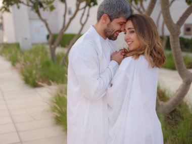 Abu Dabi 'deki Birleşik Arap Emirlikleri' ne git. Abu Dabi 'deki Büyük Cami yakınlarındaki parkı ziyaret eden Arap çift geleneksel elbiseler giyiyor..