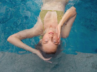Genç bir kadının sabah vakti havuzda oturduğu bir tatil sahnesi. Hafta sonu ve tatil yaşam tarzı konsepti.