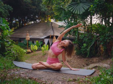 Güzel bir kadın Tayland 'da sabah havuz başında yoga yapıyor. Otelin egzotik bahçesinde spor giyim bölümünde genç bir bayan. Yoga yapan mükemmel esnek vücut iç huzuru ve canlılığı hisseder.